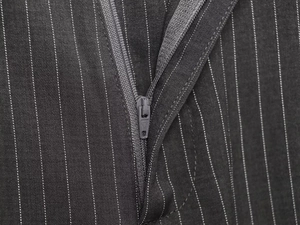 Detail of high-quality zipper and stitching on dark gray pinstripe trousers