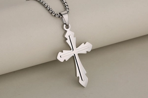 Detailed close-up of a silver stainless steel cross pendant with textured edges and chain