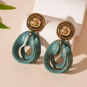 Vintage gold teardrop earrings with teal enamel and metallic spots on white stand