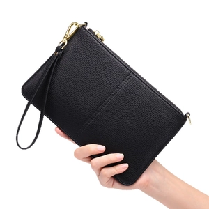 Black pebbled leather clutch bag with gold zipper and wrist strap shown in hand