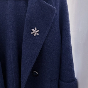 Elegant silver snowflake brooch with sparkling rhinestones on dark blue coat