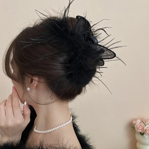 Detail of elegant black feather and mesh bunny ear hair claw clip on a model hairstyle