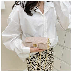 Detail of beige quilted cylinder bag with glossy finish and gold metal chain strap