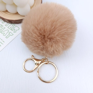 Close-up of khaki plush pompom keychain with golden metal clasp and ring detail