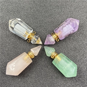 Top view of four hexagonal crystal perfume bottle pendants in various colors on black sand