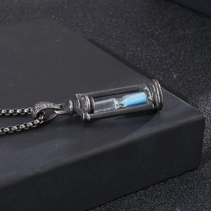 Close-up of retro stainless steel hourglass pendant with blue sand and metal box chain
