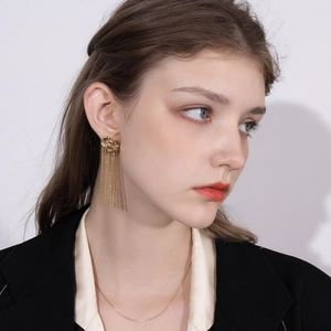 Close-up of elegant gold flower tassel earrings and matching chain necklace on model