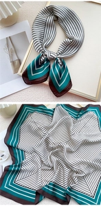 Détail du foulard en soie montrant des rayures noires et blanches et bords bleu-vert