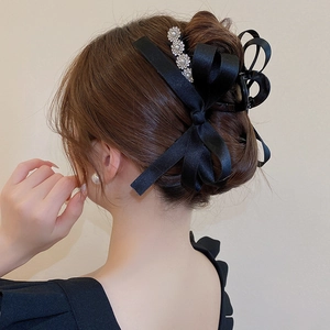 Pince à cheveux nœud en satin noir avec perles et strass sur un chignon élégant de dos
