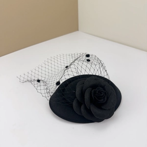 Close-up of vintage black mini top hat with 3D camellia flower and polka dot mesh veil