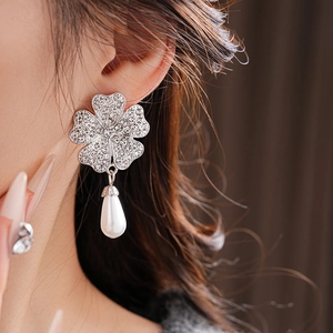 Close-up of silver clover earrings with sparkling rhinestones and white pearl drops