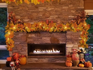 Detalle de luces LED de hojas de membrillo artificiales en una chimenea decorativa de otoño