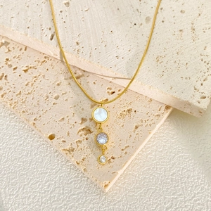 Macro detail of golden necklace with shell pendant and stacked zircon crystals on stone