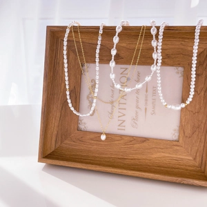 Detail of layered baroque pearl and gold bead necklaces draped on a wooden frame