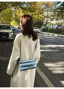 Detail of blue quilted metallic crossbody bag with slim strap in natural outdoor sunlight