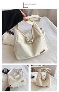 Detail of white corduroy bucket bag showing wide strap and leather brand label
