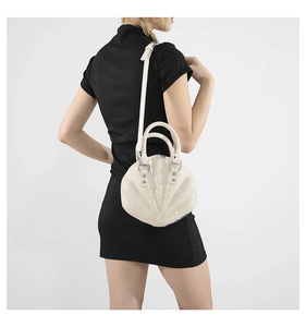 White shell-shaped handbag with 3D pattern shown on model in a sleek studio setting