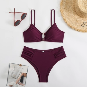 Flat lay of rose red two-piece bikini with metallic rings and summer beach accessories