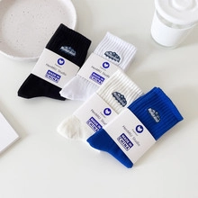 Detail of four colorful coral fleece socks with Mountain embroidery and paper packaging