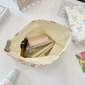Detalle del neceser de lona con estampado de lazos florales y amplia cremallera