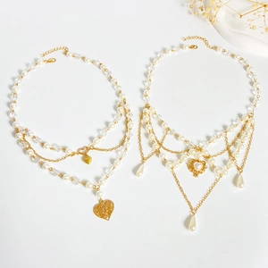 Detail of layered gold necklaces with pearl fringes and heart-shaped charms