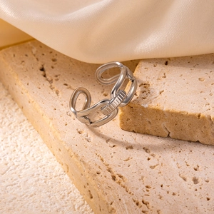 Close-up of industrial style silver steel chain ring on a beige travertine surface