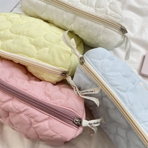 Close-up of quilted makeup bags with heart patterns and decorative zipper straps