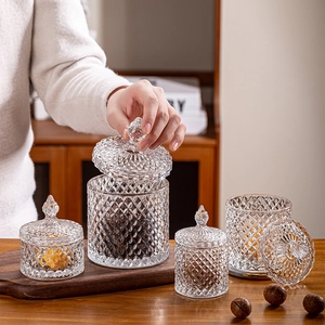 Detailed view of hand placing a lid on a large diamond-textured glass storage jar