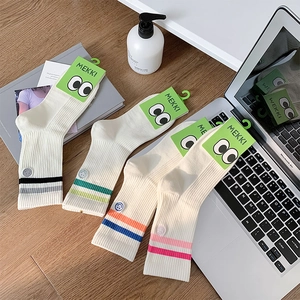 Detail of four pairs of cream athletic socks with colorful stripes and embroidery detail