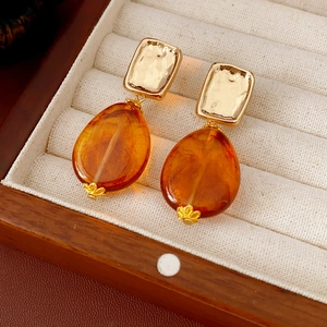 Detail of amber teardrop earrings with gold hardware in a beige velvet jewelry box
