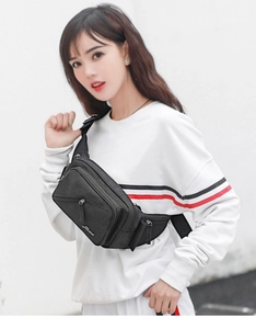 Close-up of black nylon waist bag with multiple pockets and adjustable strap shown on model