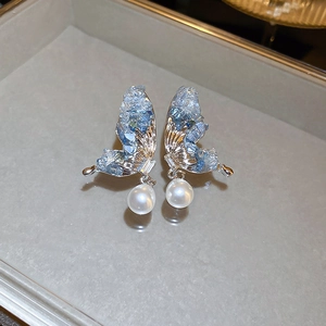 Elegant butterfly earrings with light blue inlay and pearls on a sleek grey tray