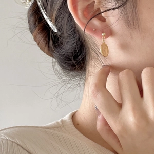Close-up of a model wearing a gold coin relief earring in vintage 925 silver style