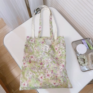 Borsa tote in tela a fiori con motivi floreali verde chiaro su un tavolo bianco pulito