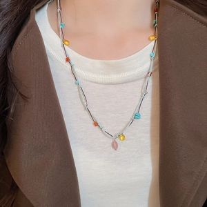 Close-up of a blue woven cord necklace with colorful turquoise and amber stone beads
