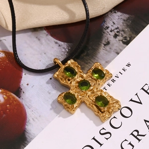 Detail of 18K gold-plated hammered cross pendant with five emerald green gemstones