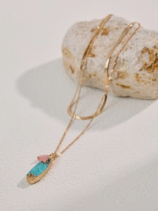 Detail of gold chain necklace with turquoise stone pendant and small pink crystal bead