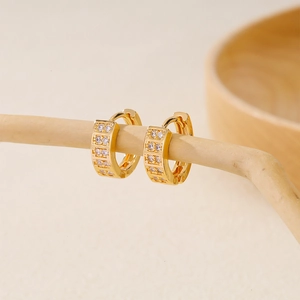 Fashionable gold plated hoop earrings with zircon stones on minimalist wood stand