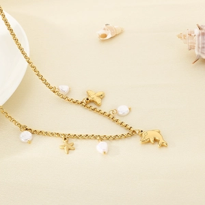 Detailed shot of golden summer necklace featuring dolphin, starfish pendants and pearls