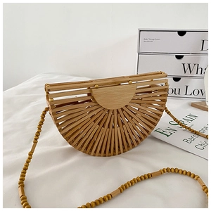 Detail of a semi-circular woven bamboo bag featuring a wooden beaded strap for beach vacations