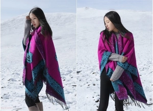 Detail of ethnic paisley shawl with black tassels and vibrant colors in snow landscape