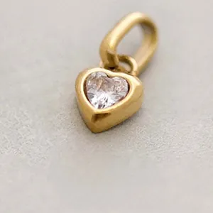 Macro view of a gold-plated heart pendant with a central heart-shaped clear gemstone