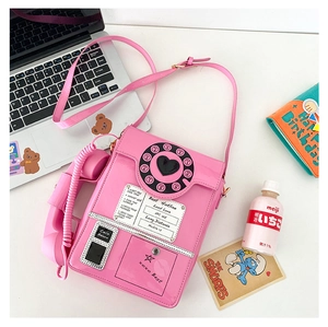 Close-up of pink retro telephone shaped crossbody bag with vintage dial and receiver detail