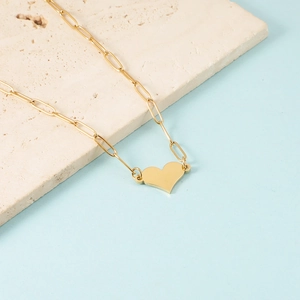 Detailed view of a gold heart pendant necklace on a paperclip chain with textured stone