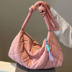 Pink quilted large capacity tote bag with knot handles and charm in minimalist setting
