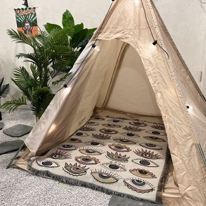 Detail of bohemian outdoor camping blanket featuring colorful eye patterns and tassels