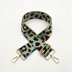 Close-up of leopard print woven bag strap with adjustable buckle and gold metal hooks