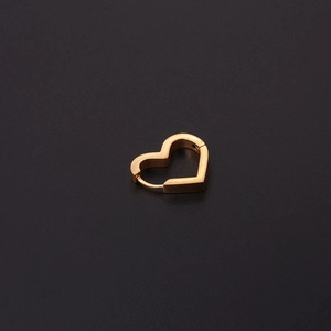 Détail d'une boucle d'oreille huggie en forme de cœur dorée mate sur un fond sombre élégant