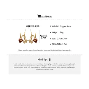 Detail view of gold-plated dog and heart earrings with size 2.7cm and weight 8.4g