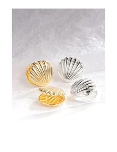Detailed view of French vintage shell-shaped gold and silver earrings on textured paper